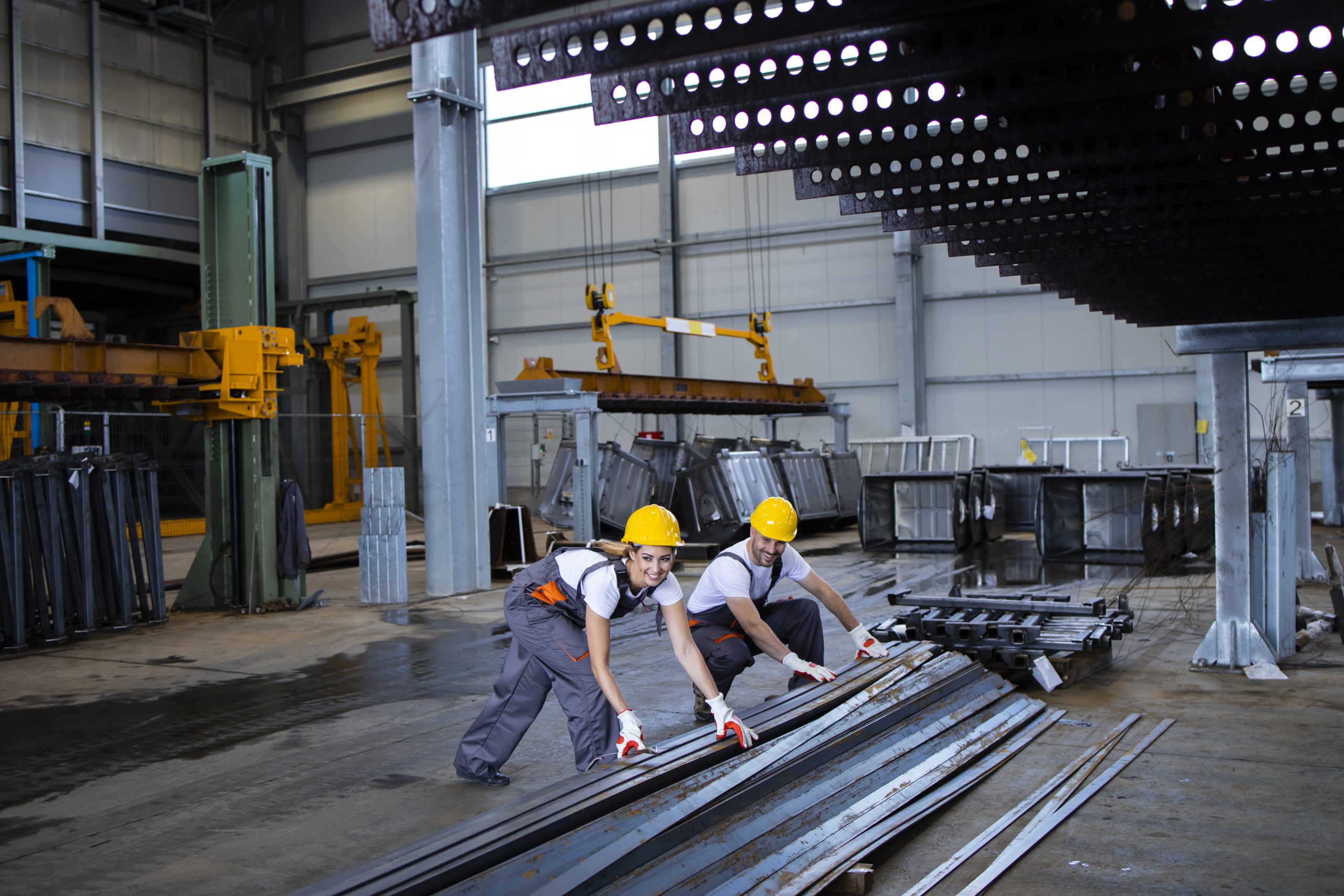 Factory workers handling metal parts together.