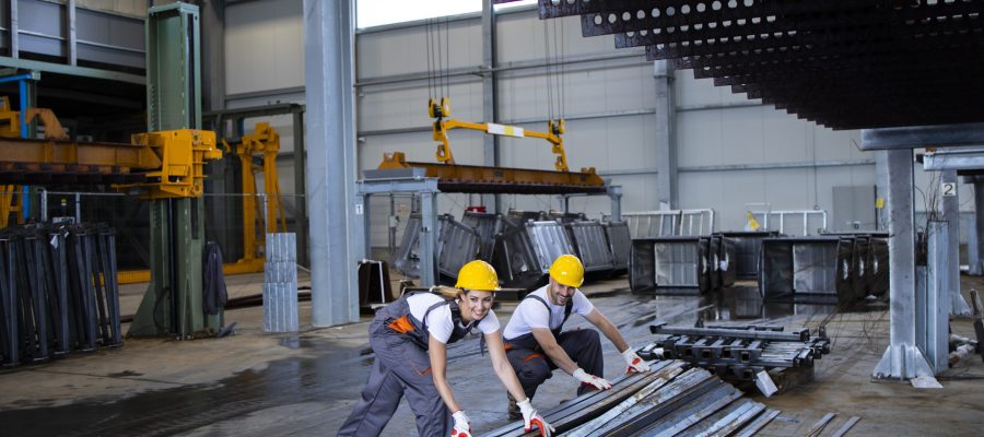 Factory workers handling metal parts together.