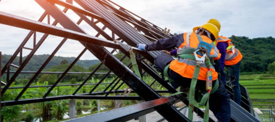 Construction worker wearing safety harness using secondary safety device connecting into 15 mm static rope using as fall restraint shingle on top of the new roof.